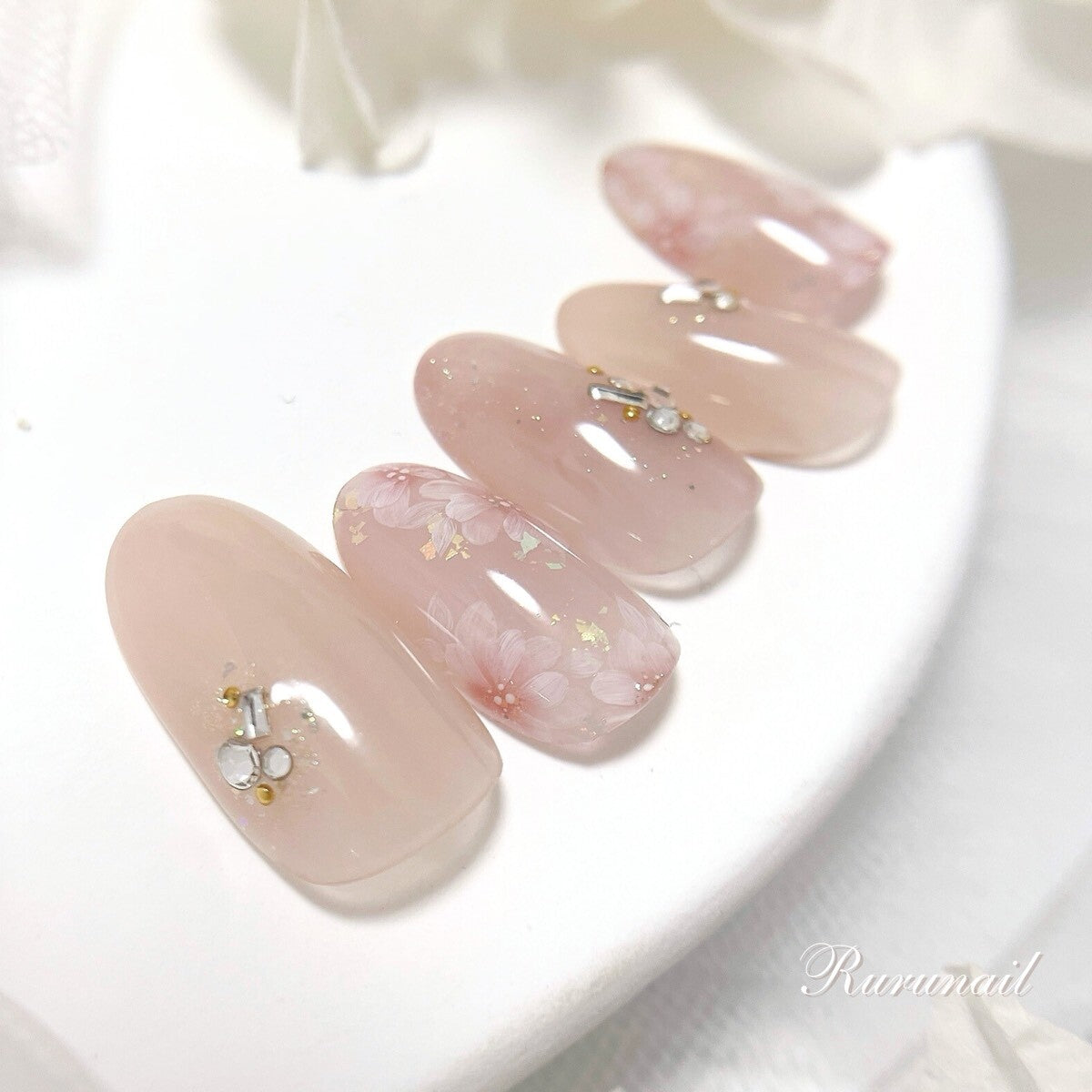 指先に溶け込む奥行きフラワーのピンクベージュネイルチップ